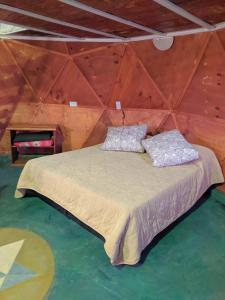 Bett in einem Zimmer mit einer Holzwand in der Unterkunft Cabaña Domo Delta in Los Cocos