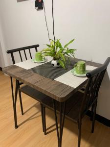 un tavolo di legno con due tazze verdi e una pianta di Tiffany's Staycation Unit 102 a Imus