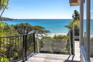 einen Balkon mit Blick auf den Strand in der Unterkunft Tawa Cottage - Coast & Country in Oneroa