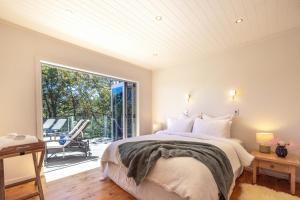 a bedroom with a bed and a large window at Tawa Cottage - Coast & Country in Oneroa