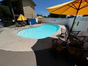 a swimming pool with chairs and an umbrella at Super 8 by Wyndham Red Bluff in Red Bluff