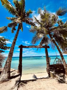 a swing on a beach with palm trees at On Board Panglao Beach Hostel & Resort in Dao