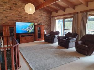 een woonkamer met lederen stoelen en een flatscreen-tv bij Beulah by the Lake in Kalkite