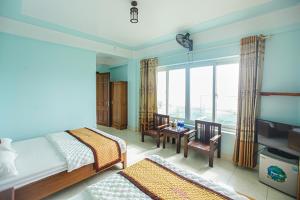 a bedroom with a bed and a desk and a window at Thành Thư Vân Đồn Hotel - by Bay Luxury in Quang Ninh