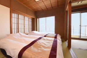 a bed in a room with two windows at Kaiyutei in Kawazu