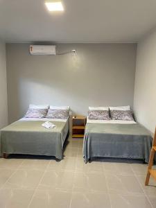 a room with two beds and a heater on the wall at Morada da Ilha Pousada in Soure