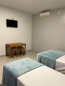 a room with two beds and a table and a television at Morada da Ilha Pousada in Soure