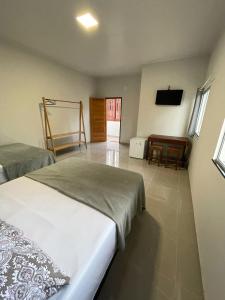 a bedroom with two beds and a table and a television at Morada da Ilha Pousada in Soure
