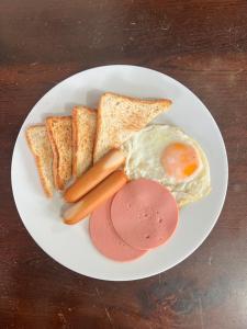 ein weißer Teller mit einem Ei, Brot und Toast in der Unterkunft Phow Homestay in Ban Mai (1)
