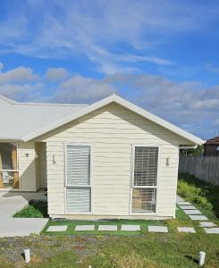 Cette petite maison blanche dispose d'une terrasse couverte. dans l'établissement Be My Guest in Beachlands, à Auckland