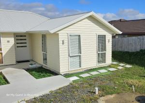 uma pequena casa branca com garagem em Be My Guest in Beachlands em Auckland