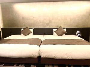 2 letti posti uno accanto all'altro in una camera da letto di Homm Stay Nagi Sanjo Kyoto By Banyan Group a Kyoto