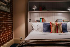 a bedroom with a bed with pillows and a brick wall at Mister Rice in Castlemaine