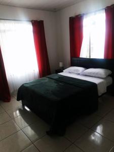 um quarto com uma cama grande e cortinas vermelhas em Casa Abundancia em Aguas Zarcas