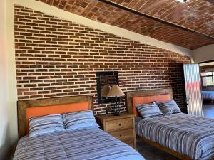 two beds in a bedroom with a brick wall at Casa San Pedro in San Pedro Tesistán +28 photos