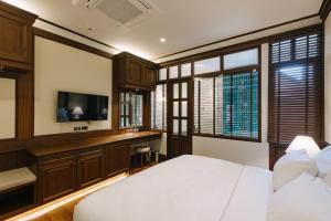 a bedroom with a bed and a desk and a television at Coucou Hotel in Chiang Mai