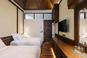 a bedroom with two beds and a flat screen tv at Coucou Hotel in Chiang Mai