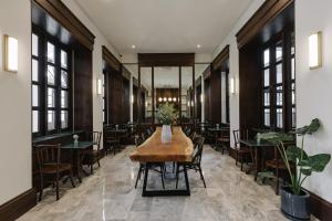ein Esszimmer mit Tischen, Stühlen und Fenstern in der Unterkunft Coucou Hotel in Chiang Mai