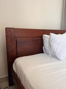 a bed with a wooden headboard and white pillows at Suite Villa au bord de la mer chez Saloua in Chirongui