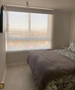 a bedroom with a bed and a large window at Departamento Vista Herradura Coquimbo in Coquimbo