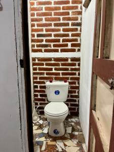 a bathroom with a toilet in front of a brick wall at Entre tejas in Concepción de Ataco