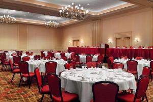 a conference room with white tables and red chairs at Augusta Marriott at the Convention Center in Augusta