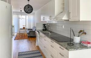 eine Küche mit weißen Schränken und ein Wohnzimmer in der Unterkunft Cozy Home In Simrishamn With Wifi in Simrishamn