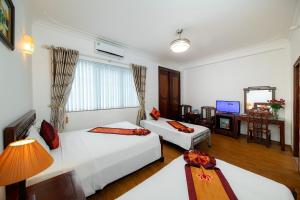 Pokój hotelowy z 2 łóżkami i biurkiem w obiekcie Phoenix Legend Hotel w mieście Hanoi