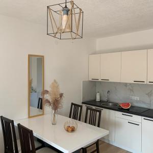 Apartman TESA في Sanski most: مطبخ مع طاولة بيضاء مع كراسي ومغسلة
