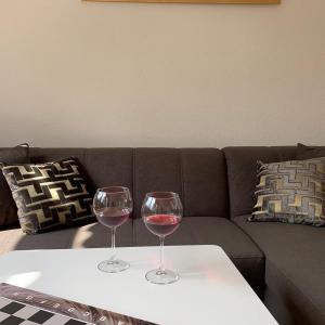 two wine glasses sitting on a table in front of a couch at Apartman TESA in Sanski most