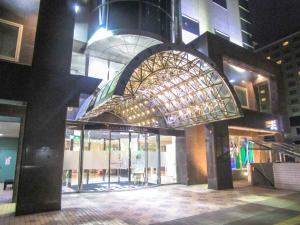 a large building with a glass entry way at night at HOTEL LiVEMAX BUDGET SAPPORO in Sapporo