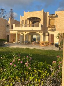a house with a yard with flowers in front of it at Chalet Marina Alamein first row sea view 3 bedroom-North Coast in El Alamein