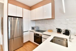 奥克兰Ocean View Retreat - Orewa Beach的配有白色橱柜和不锈钢冰箱的厨房 更多13张照片