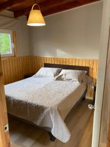 a bedroom with a bed with a white comforter at El Viloche - Tiny House in Puerto Montt