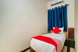 - une chambre dotée d'un lit rouge et blanc avec des rideaux bleus dans l'établissement OYO Flagship 26817 Gks Residency, à Bangalore