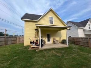 a yellow house with a porch with a motorcycle on it at ComfyStay in Gladewater