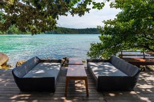 duas cadeiras e uma mesa numa doca ao lado de um lago em Captain Hook Resort @Koh Kood em Ko Kood