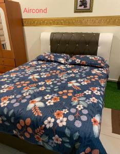 a bed with a blue quilt with flowers on it at homestay sayangku islam in Segamat