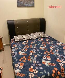 Bett mit blauer Blumendecke und 2 Kissen in der Unterkunft homestay sayangku islam in Segamat