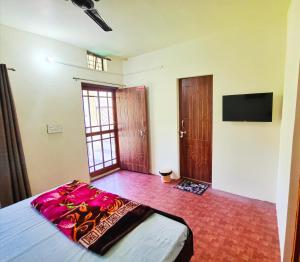 a bedroom with a bed and a flat screen tv at Alaknanda Homestay in Karnaprayāg