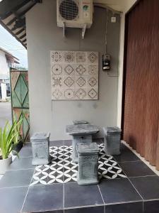 eine Terrasse mit einem Tisch und 2 Hockern auf einem Fliesenboden in der Unterkunft De Patuk Homestay in Yogyakarta