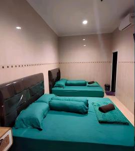 2 camas en una habitación con almohadas verdes en De Patuk Homestay en Yogyakarta