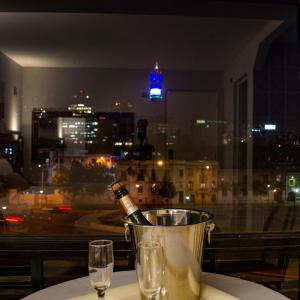 a bottle of wine in a bucket on a table with glasses at Red Hotel Centric Santiago in Santiago