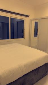 ein weißes Bett in einem Zimmer mit 2 Fenstern in der Unterkunft دلتا2للوحدات المخدومة بالدوادمي in Ad-Dawādimi