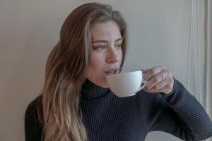 una mujer bebiendo de una taza de café blanca en Red Hotel Centric Santiago, en Santiago