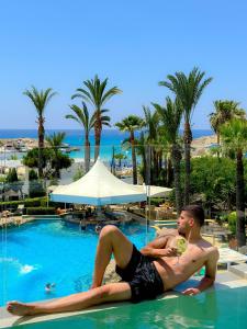 two men laying in the swimming pool at a resort at Tasia Maris Beach Hotel - Adults Only in Ayia Napa