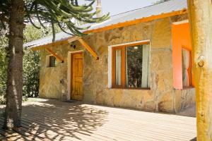 Casa de piedra con puerta de madera y porche en Sueño de Pehuenia en Villa Pehuenia