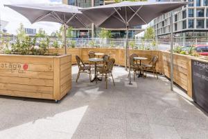 an outdoor seating area with tables and chairs and umbrellas at Rydges Perth Kings Square in Perth