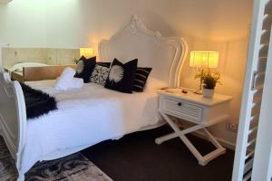a bedroom with a white bed with pillows and a table at Villa by the Sea in Mandurah +37 photos