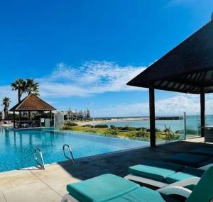 a swimming pool with lounge chairs next to the ocean at Villa by the Sea in Mandurah